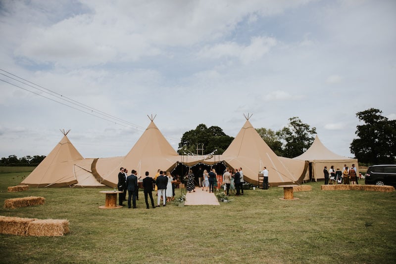 Guests Arriving at The Two giant hats and chill-out tipi wedding celebration at Cuttle Brook. This waterfront wedding venue offers a relaxed wedding setting.