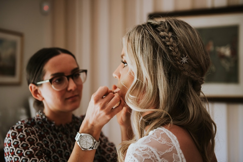 Bride getting ready finishing touches by makeup artist