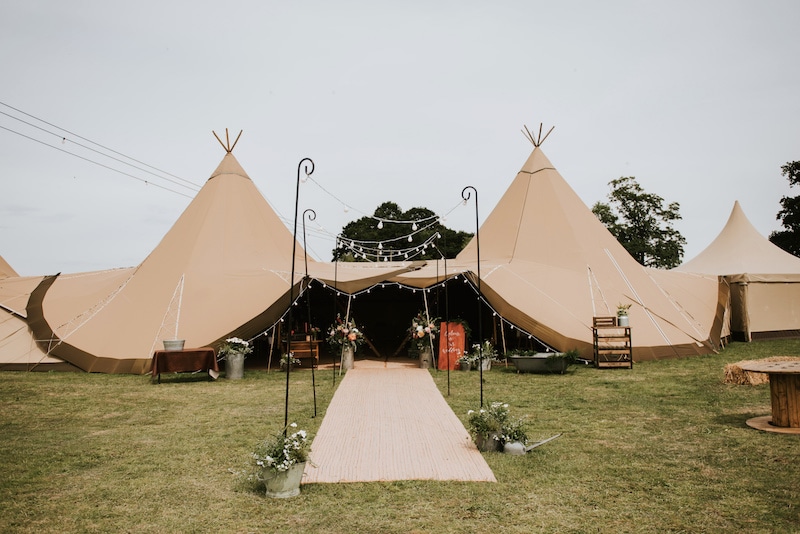 2 giant hats and chill out tipi Tipi entrance with florals and festoon walkway