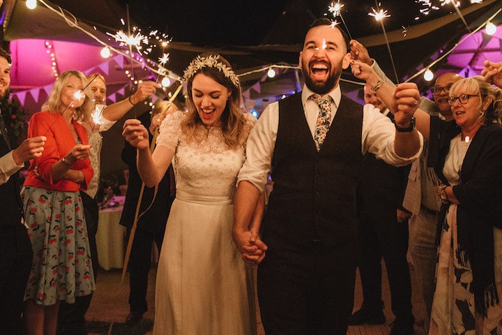 couple enjoying a sparkler send off in front of their tipis