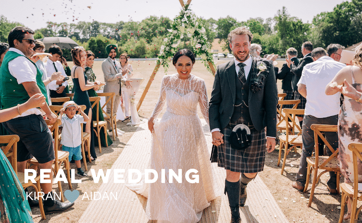 Happy couple, just married walking down the aisle with guests throwing confetti over them. Very sunny