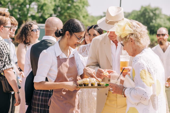 9 Top Tips For Coping With Hot Weather. Waitress giving out canapés to two guests in the sunshine. 