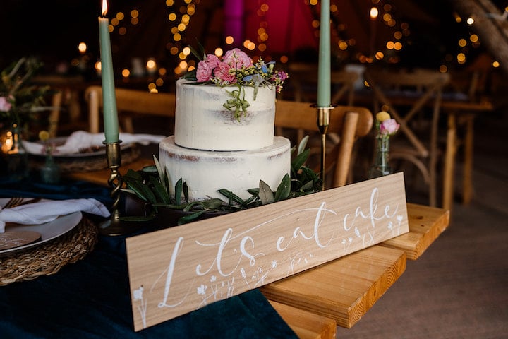 Spring Tipi Styling wedding cake with sign "lets eat cake" complete with hand-letterin spring flowers